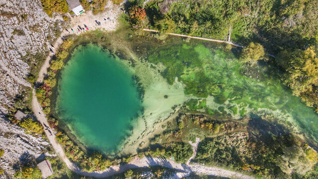 Aerial view of the Eye of the Earth spring, a karst water source with vibrant turquoise and green hues, surrounded by rocky terrain and trees in Cetina, Sibenik-Knin County, Croatia.