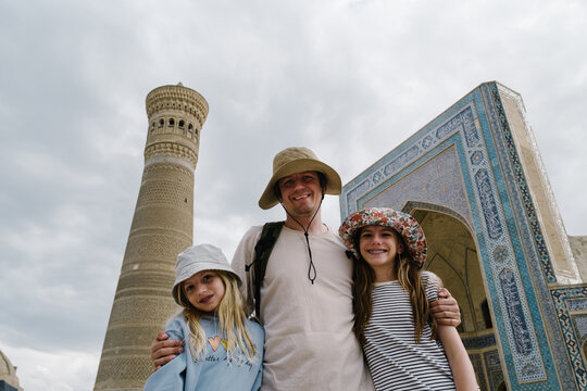 Father and daughters smiling at the Po-i-Kalyan complex in Bukhara.