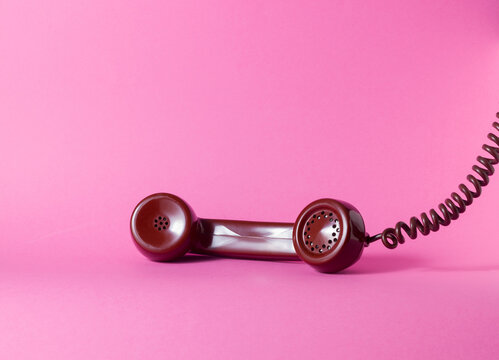 Vintage Telephone Handset Resting on Bright Pink Background