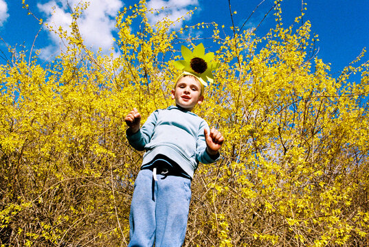 Happy jumping boy with yellow spring flowers