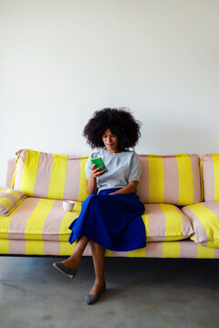 Woman Relaxing on Yellow Striped Sofa With Phone
