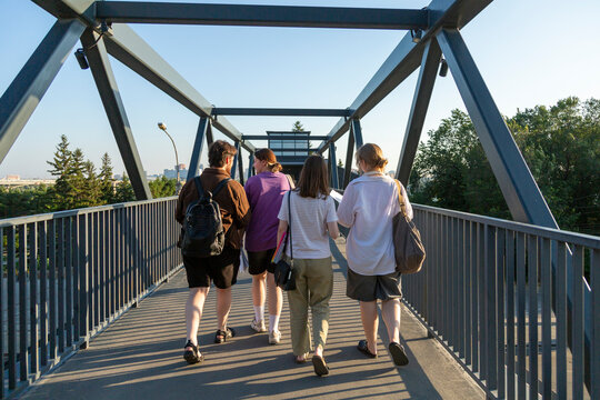 Four students walking together across pedestrian bridge