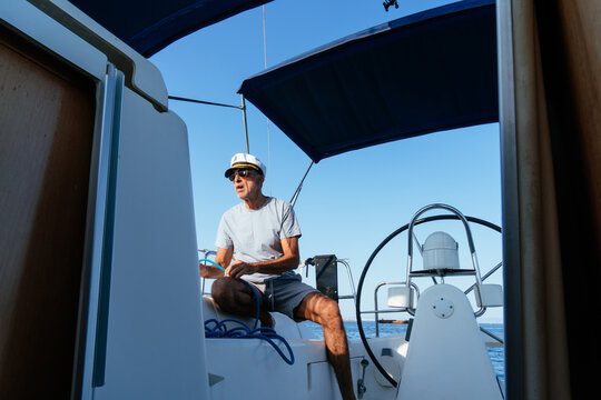 Senior man steering a sailboat on summer vacation