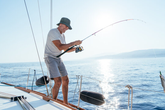 Man fishing from sailboat enjoying summer sea activity