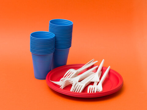 Colorful Disposable Plastic Tableware Set on Bright Orange Background