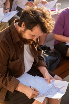 Student writing on exam paper during group study session