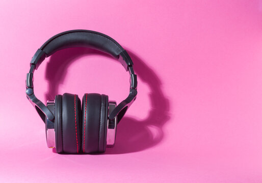 Front View of Black Audio Headphones on Bright Pink Background