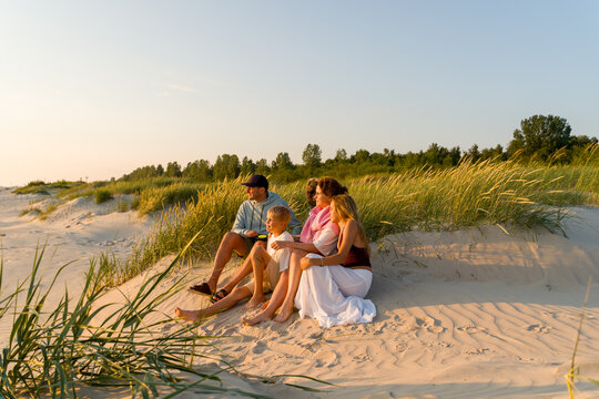 Family Watching Sunset on Sandy Beach at Summer