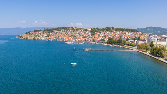 Aerial view of Ohrid Old Town with its historic red-roofed houses, ancient fortifications, and the sparkling blue waters of Lake Ohrid in Ohrid, Municipality of Ohrid, North Macedonia.