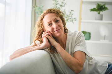 50s woman resting on comfortable sofa.