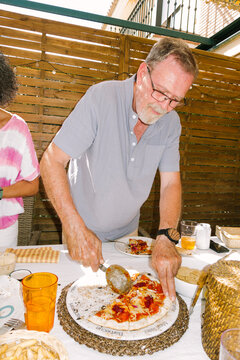 Man Serves Pizza at Outdoor Dining Table