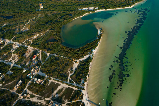 Aerial view of Isla Holbox featuring turquoise waters, lush mangrove forests, and sandy paths along the coastline in Isla Holbox, Quintana Roo, Mexico.