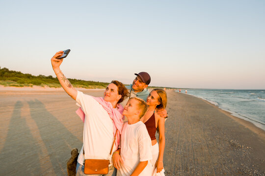 Family Take a Selfie on the Beach During Sunset