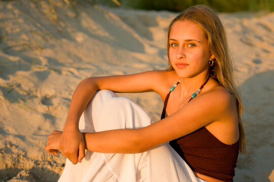 Girl Sitting on the Beach at Sunset in Warm Light