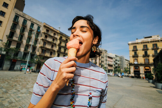 Woman enjoying delicious ice cream cone in urban city