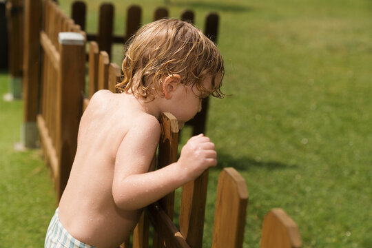 Child playing by a wooden fence in a sunny park