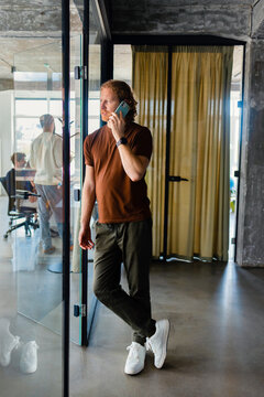 Businessman On Phone Standing In Modern Office