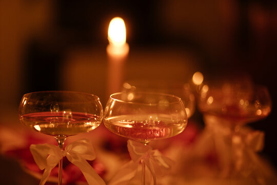 Elegant champagne glasses with ribbons on a table, soft candlelight creating a warm ambiance, blurred background highlights romantic setting for special occasions