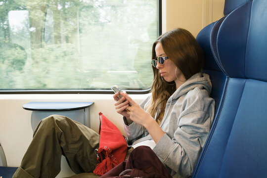 Woman uses phone while sitting in a train seat on a journey