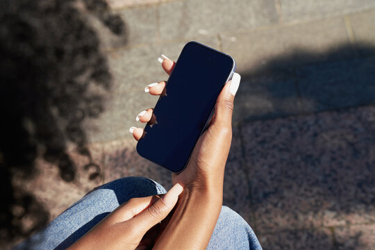 Person holding a phone while sitting outdoors