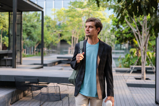 A stylish man walks through a modern outdoor space