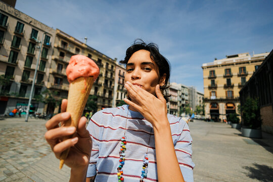 Woman refreshing ice cream cone in city street