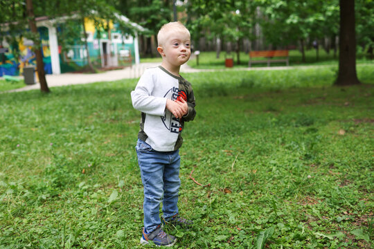 A child with Down syndrome is walking in the park.