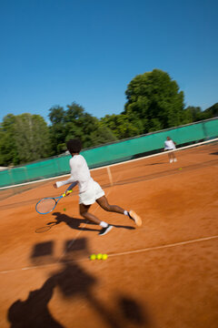 Black man tennis player blurred into motion with racket and ball.