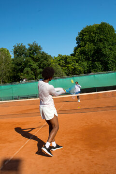 Black man tennis player blurred into motion with racket and ball.