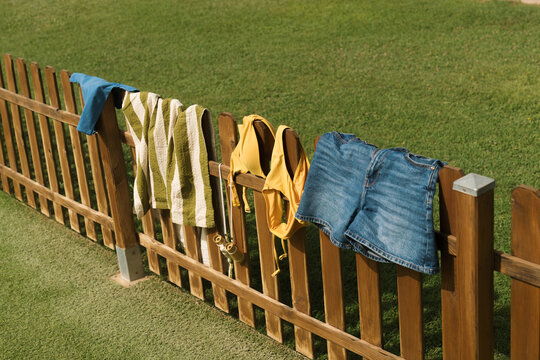 Clothes hanging on a wooden fence in a sunny outdoor setting