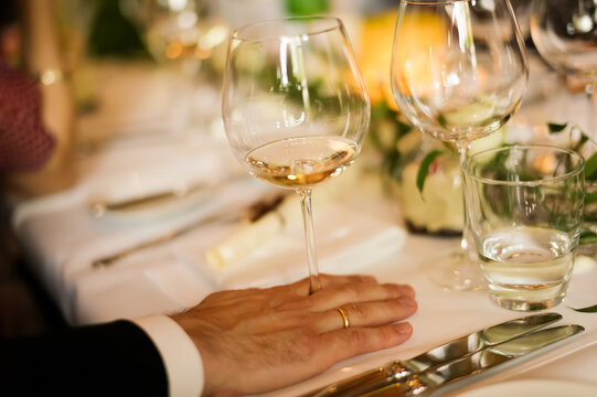 Elegant dinner setting with wine glass and careful hand placemen