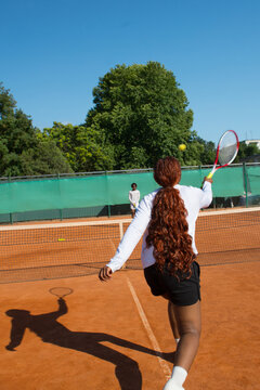 Black woman tennis player blurred into motion with racket on court.