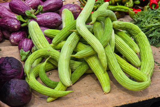 Fresh organic Armenian cucumbers, purple eggplants, and red cabbage at a Mediterranean farmers market in the daytime