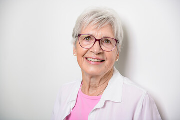 Fototapeta premium Portrait of elderly woman with eyeglasses over studio white