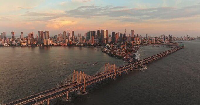 A breathtaking aerial drone view of Mumbai City during the golden evening in the monsoon season, featuring the iconic Bandra-Worli Sea Link stretching across the Arabian Sea.