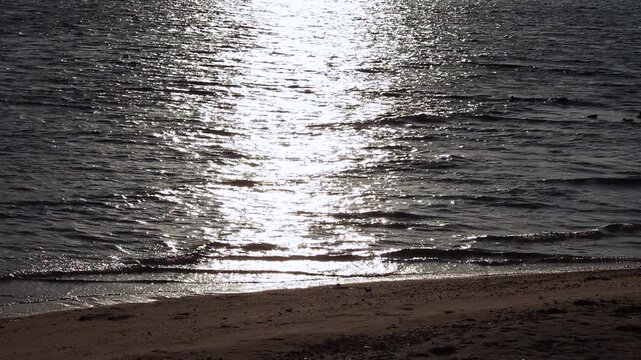 波打ち際の水面が夕方の光を受けて輝く海辺の景観