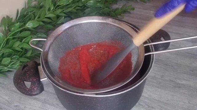 Straining Fresh Strawberry Puree Through Sieve for Homemade Jello Dessert