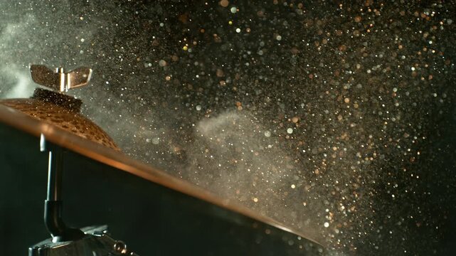 Super slow motion footage at 1000 fps of golden glitter and white powder flying above a vibrating cymbal, capturing sparkling particles, dust, metallic movement, and dynamic energy.