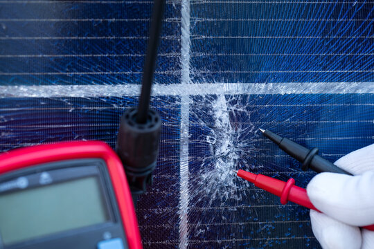 Technician Testing a Cracked Solar Panel with Multimeter Probes