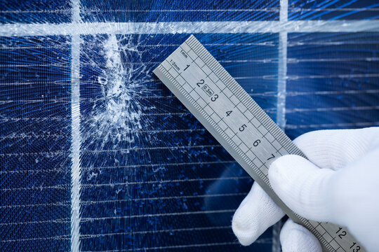 Technician Measuring Impact Damage on a Cracked Solar Panel