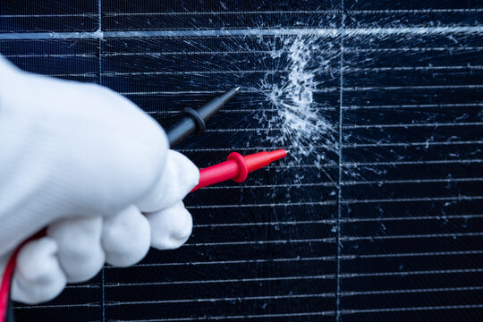 Technician Testing a Cracked Solar Panel with Multimeter Probes