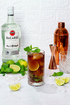 Making a Cuba libre cocktail, with Bacardi rum, limes, mint and ice, harsh light, no people.