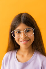 Obraz premium little brunette girl in glasses for vision against a yellow background