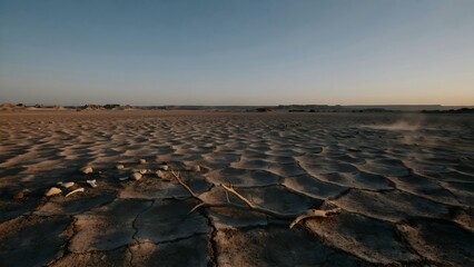 Obraz premium Expansive arid desert landscape with cracked earth and distant horizon at sunset