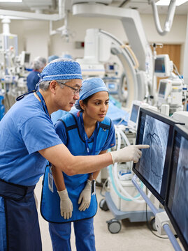 Cardiologists analyzing coronary angiogram monitor in modern hospital cath lab