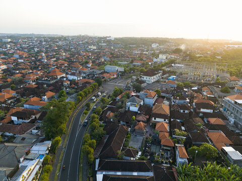 Aerial view of the Nusa Dua Substation surrounded by dense residential neighborhoods with red-tiled rooftops, lush greenery, and a winding road in Kecamatan Kuta Selatan, Bali, Indonesia.
