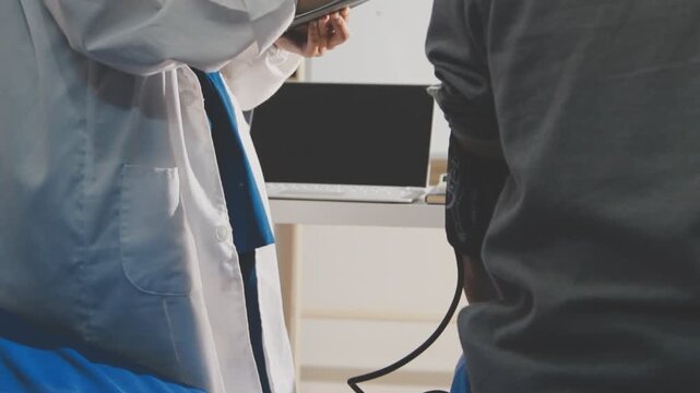 senior using a blood pressure cuff during a telemedicine consultation via digital tablet at home.