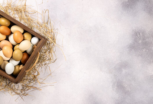 Fresh organic farm eggs in wooden box with straw