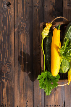 Fresh harvest zucchini and squash with flowers in rustic crate