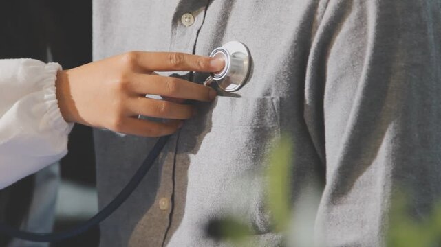 Doctor use stethoscope, checking up heart beat, auscultation in doctor office at hospital. Patient worker has to get medical checkup every year for her health or